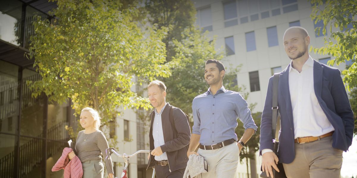 Ein internationales Team ist gemeinsam auf dem parkähnlichen Gelände des Business Campus Unterschleißheim unterwegs