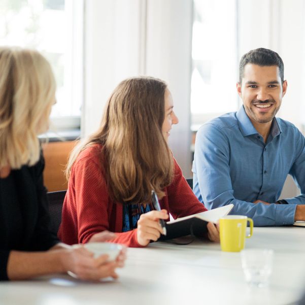 Junges Management Team sitzt im hellen Meetingraum im Business Campus Unterschleißheim und tauscht sich aus